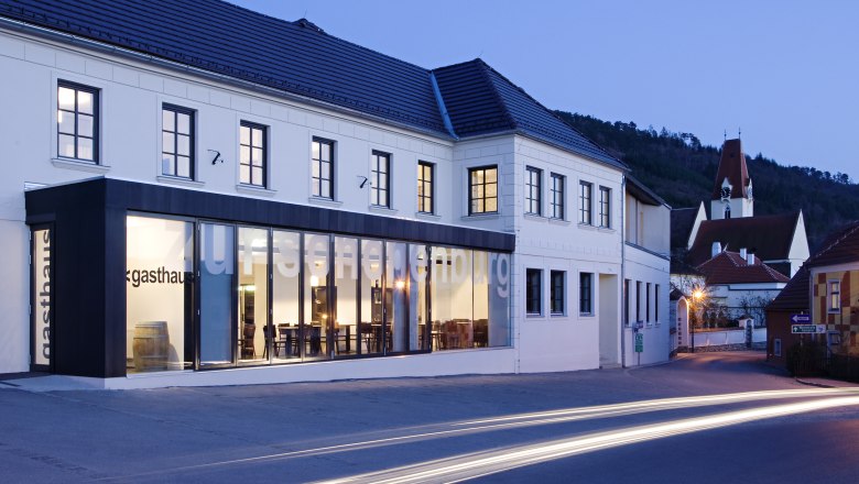 "Zur Schonenburg" Inn and Hotel, © Gasthof Hotel "Zur Schonenburg" Exterior view of the Gasthof Hotel Zur Schonenburg at dusk with illuminated windows and passing cars.