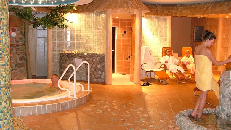 Wellness area, © Scharfegger´s Raxalpen Resort A wellness area with whirlpool, loungers and people in bathrobes.