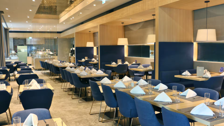 Screenshot 2026-07-17 131125, © Hilton Garden Inn A modern restaurant with blue chairs, interior view