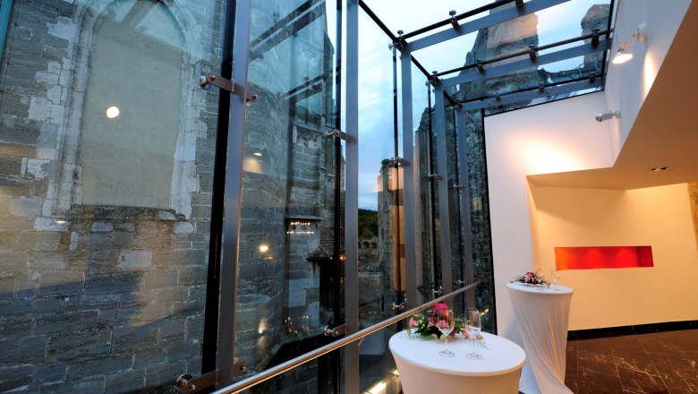 BURG Perchtoldsdorf Castle, © Manfred Horvath Modern glass architecture next to an old stone wall with decorated bar tables.