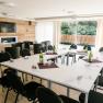 R&R Residences Hotel, © Doris Schwarz-König Conference room with U-shaped table arrangement, chairs, wooden wall, TV and large windows with a view of the greenery.