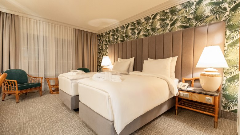 Eventhotel Pyramide, Rooms, © Eventhotel Pyramide GmbH Hotel room with two single beds, tropical wallpaper and bedside lamps.