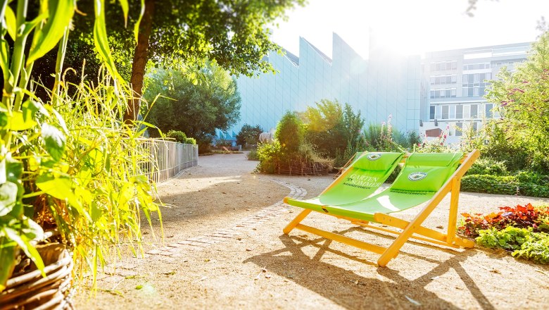 Museum Niederösterreich, Garden, © Andreas Gießwein Garden area of the Museum Niederösterreich with green deckchairs and plants in the sunlight.