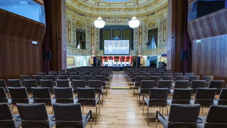 Conference Center Laxenburg, Theatersaal, © Hans Krist Interior view of a theater hall with rows of chairs, a stage and a large screen.
