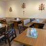 Breakfast area, © Wiener Alpen Cozy breakfast area with wooden tables and upholstered benches, decorated with wall ornaments.