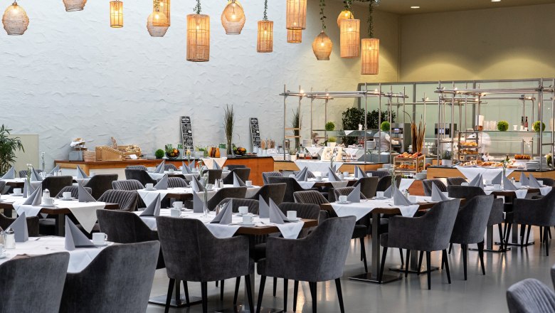 Eventhotel Pyramide, Hemingway Restaurant, © Eventhotel Pyramide GmbH Interior view of a stylish restaurant with laid tables and hanging lamps.