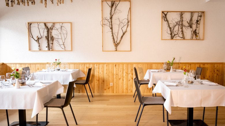 Parkhotel Hirschwang, Raxblick Restaurant, © Friedl und Schmatz Elegant restaurant with wooden walls, white tablecloths and birch art on the walls.