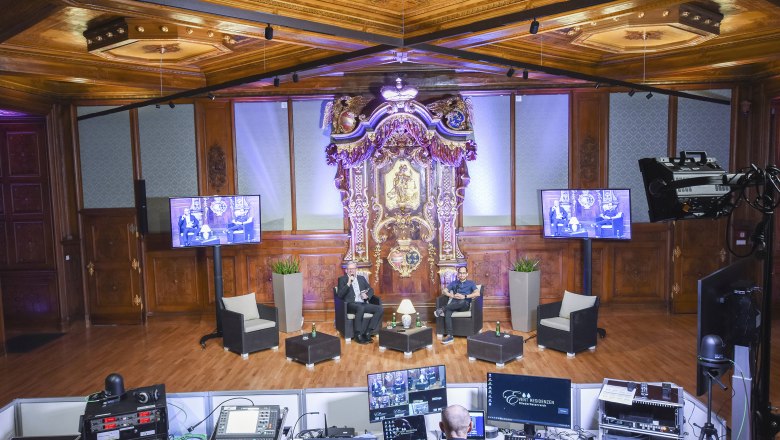 Palais Niederösterreich, Studio 13, © Event Residenzen Niederösterreich An opulent room with wood paneling and an elaborate altar. Two people sit on a stage, surrounded by technology and screens.