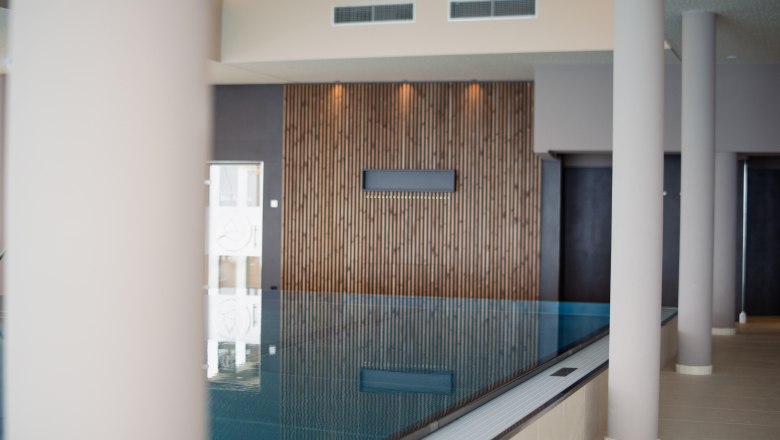 Infinity pool inside Hotel Schachner, © Hotel Schachner_MIKU Media Interior view of an infinity pool at the Hotel Schachner with wooden cladding and modern columns.