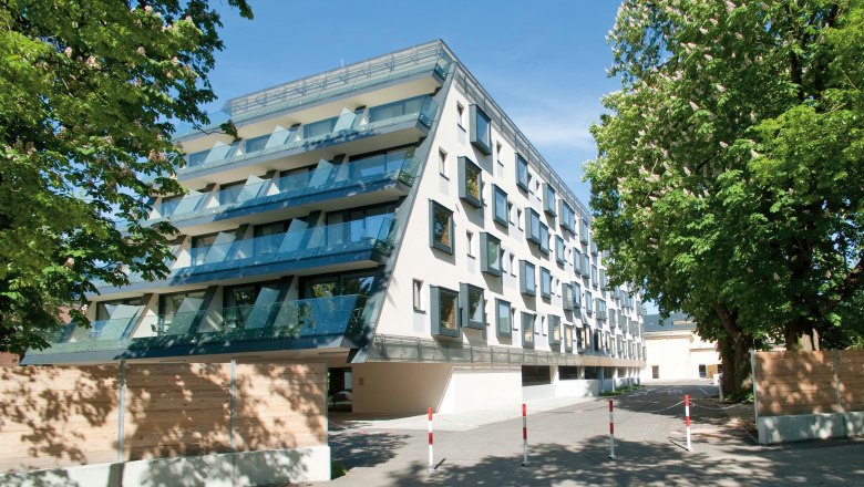 Hotel in the center of St. Pölten, © Cityhotel D&C St. Pölten Modern hotel building with glass balconies and trees in the foreground.