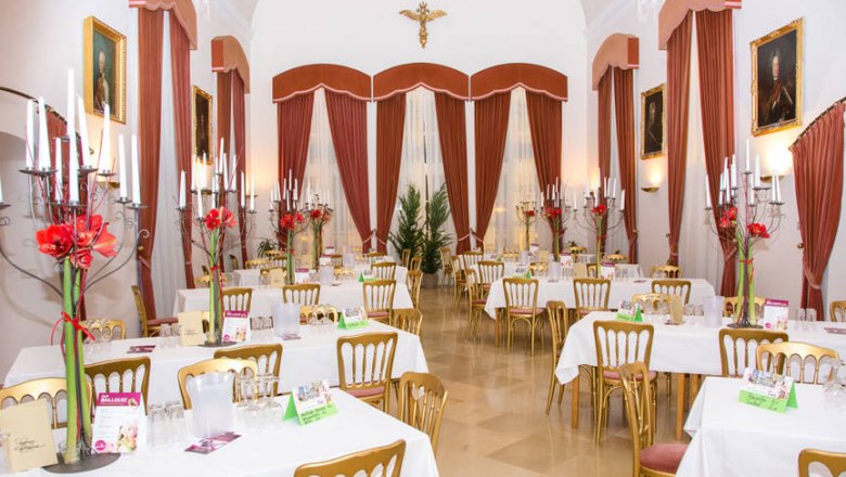 Minoritensaal Tulln, © Fischer-Media.at Elegant hall with laid tables, candlesticks and red curtains.