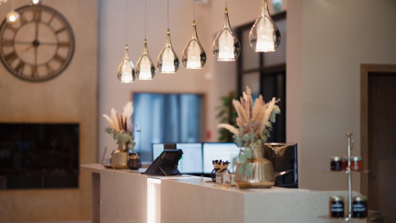 Reception Hotel Schachner, © Hotel Schachner_MIKU Media Elegant hotel reception with modern lamps and decorations.