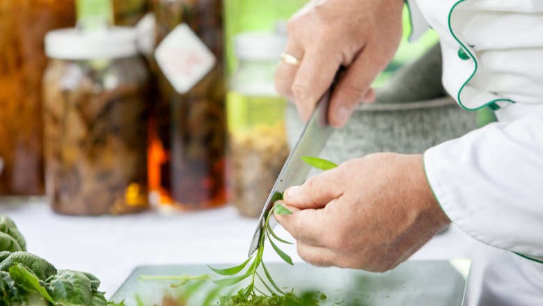 Nature in the garden, © "Natur im Garten" Schaugärten, Florian Lierzer Person cuts fresh herbs with a knife.