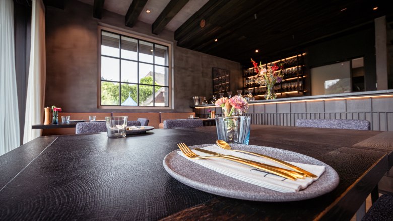 Refugium Lunz, © Niederösterreich Werbung / Maximilian Pawlikowsky Elegant restaurant with laid table, gold-colored cutlery and flowers.