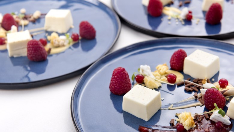Trabitsch Catering, © Trabitsch Catering Elegant dessert presentation on blue plates with raspberries, cream and chocolate chips.