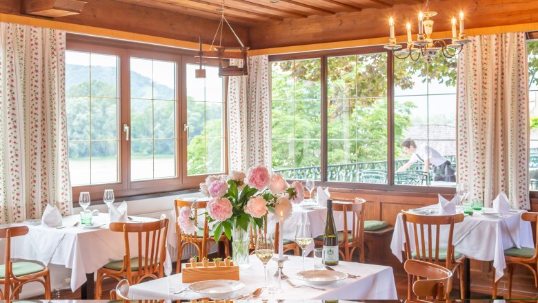 Restaurant Hotel Richard Löwenherz, © Chris Saupper Elegant restaurant with laid tables, flowers and views of nature through large windows.
