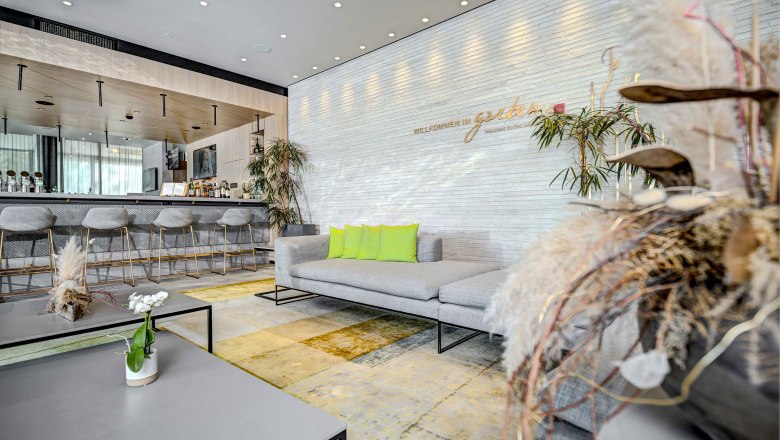 Hilton Garden Inn Wiener Neustadt, © Hilton Garden Inn Wiener Neustadt Modern hotel lobby with bar, gray sofas and green cushions at the Hilton Garden Inn Wiener Neustadt.