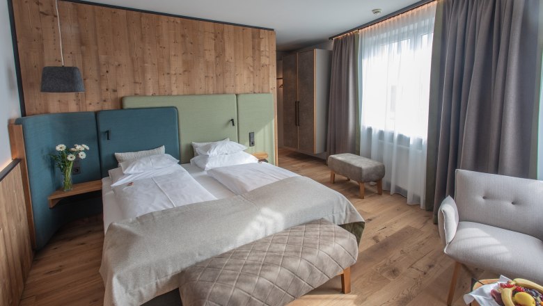Sole Felsen Hotel, © Sole Felsen Welt, Peter Baier Modern hotel room with double bed, wooden walls and large windows.