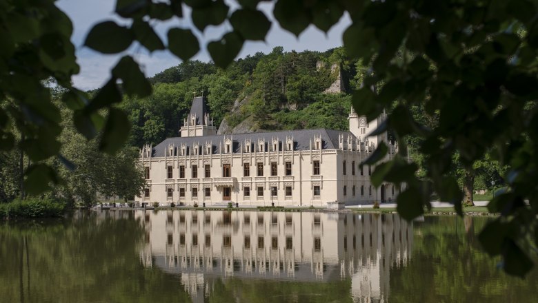 Schloss Hernstein, © Eva Heindl_alt Schloss Hernstein is reflected in a lake surrounded by trees.