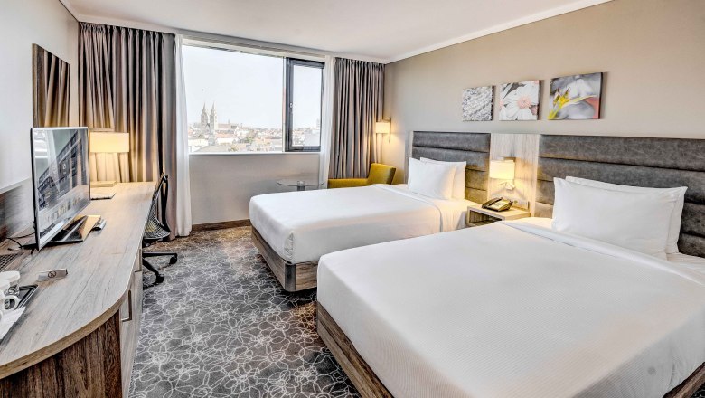 Hilton Garden Inn Wiener Neustadt, © Hilton Garden Inn Wiener Neustadt Hotel room with two beds, desk and window with city view.