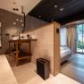 Modern hotel room with open bathroom, wooden floor and large windows with a view of the greenery.