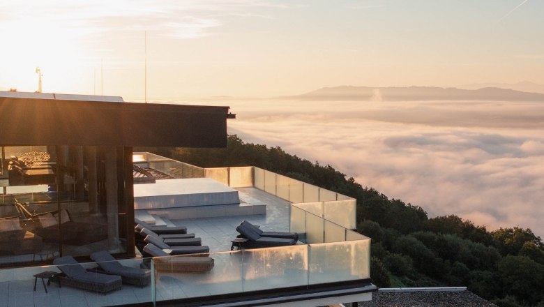 Modern building with terrace above a sea of fog at sunrise.