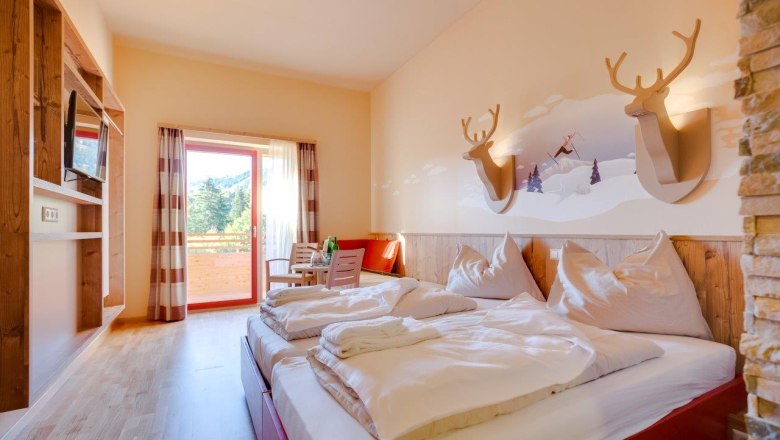 Hotel room with double bed, wooden furniture and balcony with mountain view.