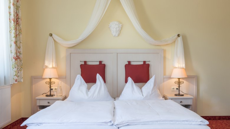 Room view with four-poster bed and red upholstery