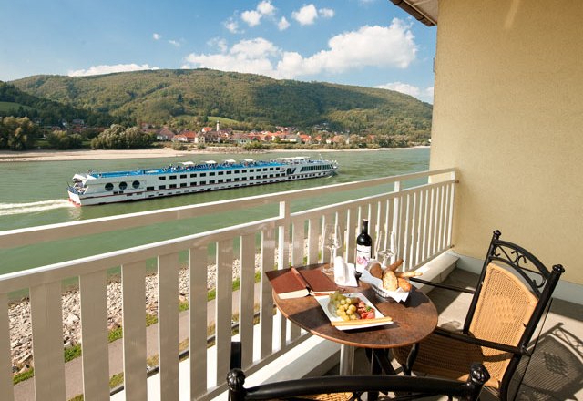 Balcony with table, wine and snacks, view of the river and passing ship.