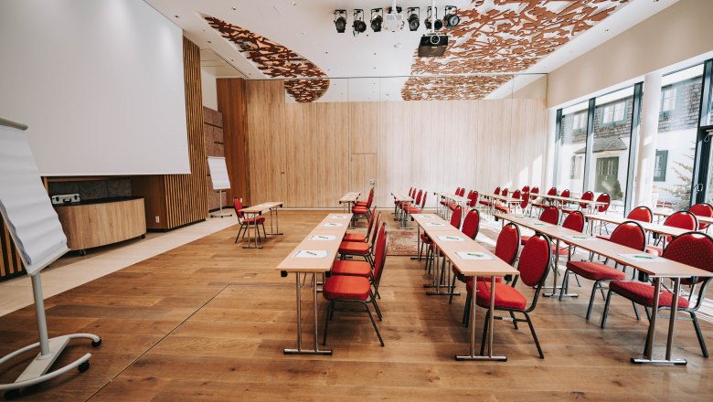 Interior view of a modern conference room with red chairs and wooden floor.