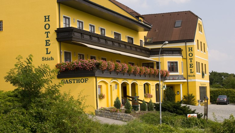 Yellow hotel building with flowers on the balcony.