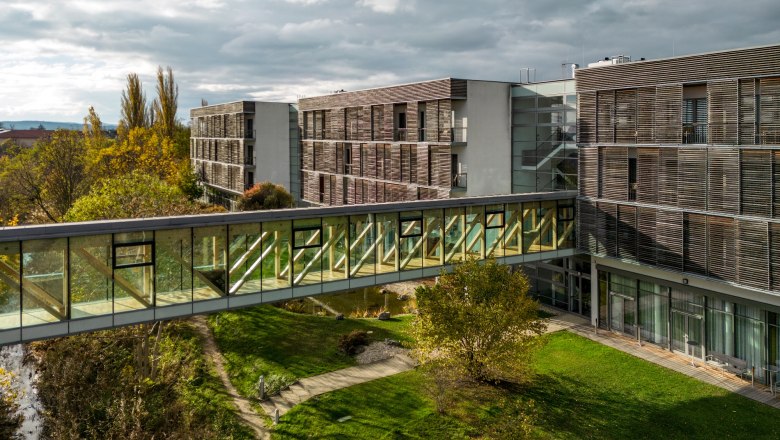 Modern hotel building with glass bridge and garden.