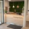Reception with wooden counter and green moss wall in the background.