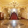 Elegant lobby with red carpet, staircase and chandelier.