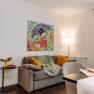 Living room with gray sofa, colorful comic art on the wall, yellow curtains and breakfast table.