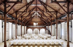 Interior view of a large banqueting hall with wooden beamed ceiling and covered tables.