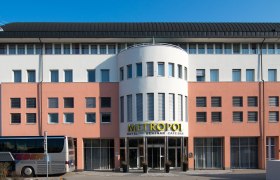 Facade of the Hotel Metropol with bus in the foreground.