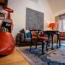 A stylishly furnished hotel room with a large red shoe as a bookshelf, antique chairs, a table and a floor lamp.