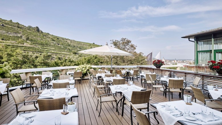 Restaurant terrace with covered tables and views of the vineyards.