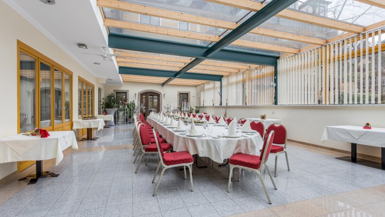 Elegant conservatory with table setting and red chairs.