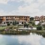 Hotel building with natural pond and sun loungers in the foreground.
