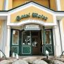 Entrance to Hotel Moser with yellow fa&ccedil;ade and green doors.