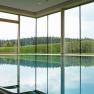 Indoor pool with large windows and views of the forest and hedges.