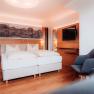 Modern hotel room with double bed, wooden floor and wall decoration.