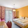 Hotel room with double bed, yellow walls, red sofa and balcony.