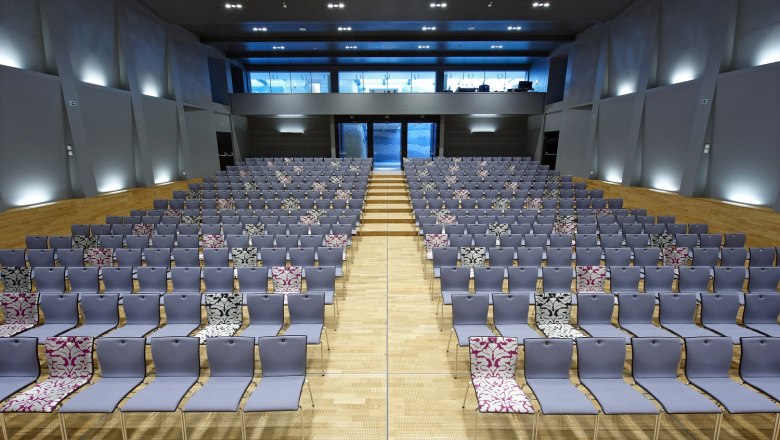 Modern hall with many empty rows of chairs, some with patterned covers.