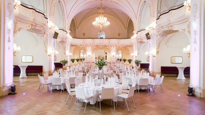 Elegant hall with laid tables and chandeliers.