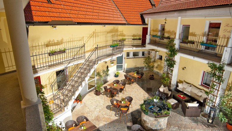Inner courtyard of the Wachau Residence with tables, chairs and a fountain.