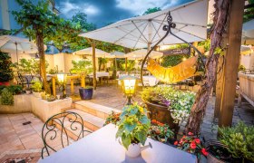 Guest garden in the evening with lighting and plenty of seating, plants and umbrellas.