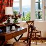 An elegant room with wooden furniture, a desk, chairs and a window overlooking a green landscape.